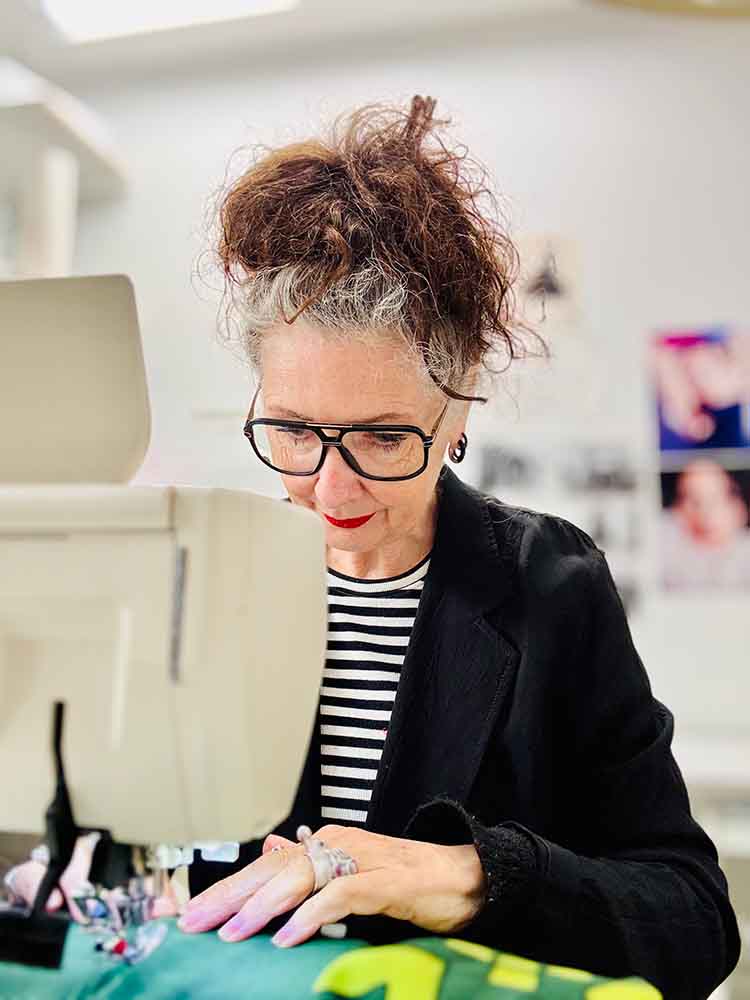 Modeontwerpster Claudia Träumer geconcentreerd aan het werk achter de naaimachine in het CLAU-D atelier, waar zij zorgvuldig een grafisch patroon stikt voor een reverse appliqué sweater.
